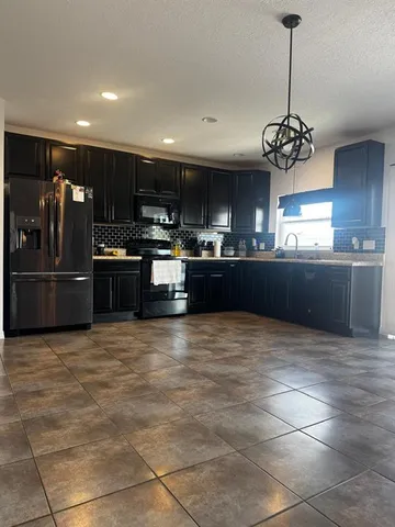 a large kitchen with granite countertop a stove and refrigerator