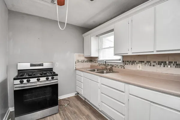 a kitchen with stainless steel appliances a stove and white cabinets