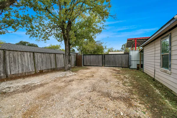 a view of a backyard with large trees and wooden fence