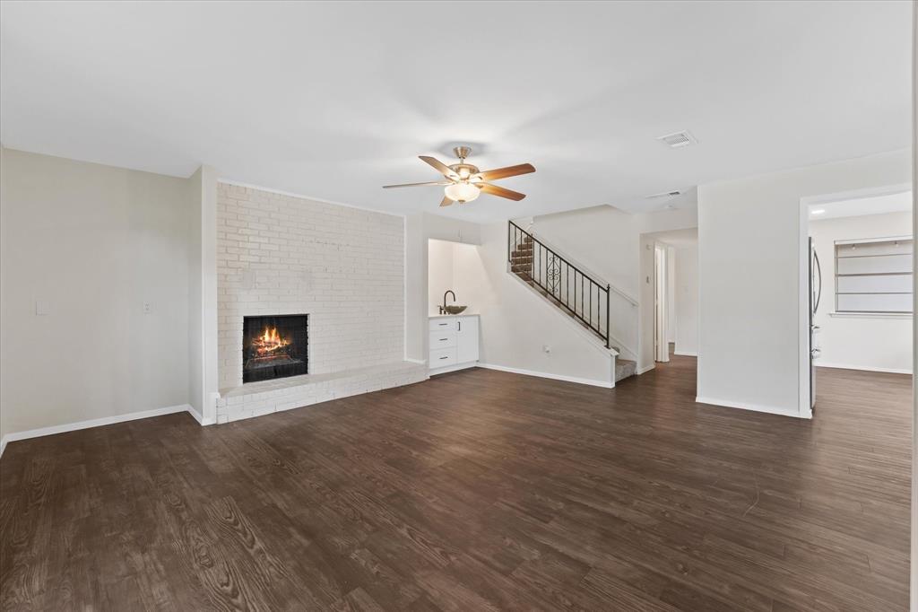 4007 Ridgebrook Drive Arlington, TX 76015 - Photo 3 of 18 Spacious living area featuring wood-finish flooring, a white brick fireplace, and a built-in wet bar with white cabinetry