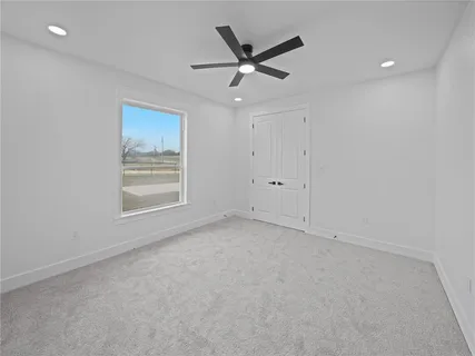 an empty room with a ceiling fan and window