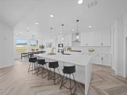 a kitchen with a dining table chairs wooden floor appliances and cabinets
