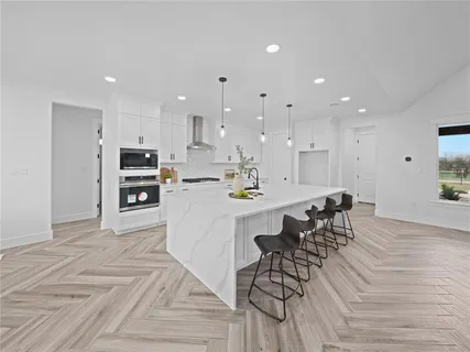 a large white kitchen with lots of counter space and stainless steel appliances