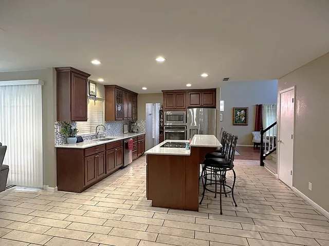 a kitchen with stainless steel appliances kitchen island granite countertop a table chairs sink and cabinets