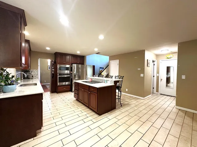 a kitchen with stainless steel appliances kitchen island granite countertop a refrigerator and a sink