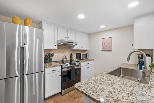 a kitchen with stainless steel appliances granite countertop a refrigerator sink and stove