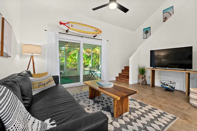 a living room with furniture a flat screen tv and a floor to ceiling window