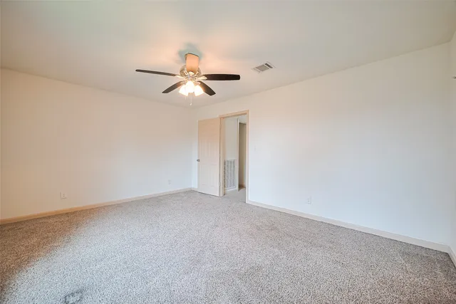 an empty room with a ceiling fan and window