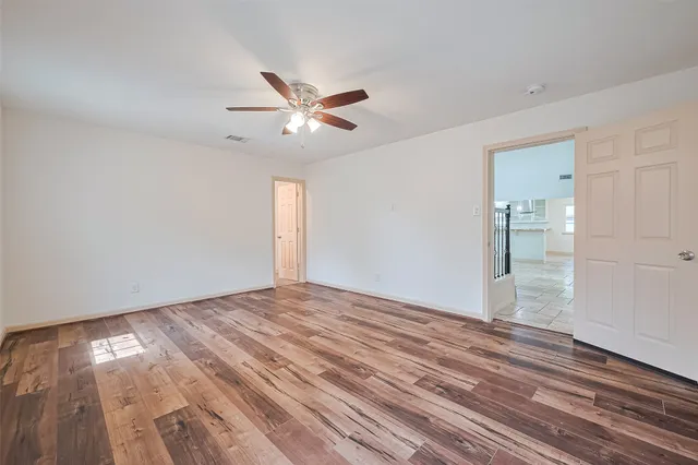 a view of empty room with wooden floor and fan
