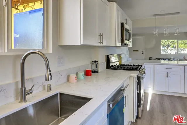 a kitchen with granite countertop a sink a stove and cabinets