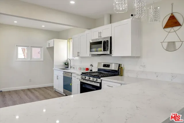 a kitchen with granite countertop a stove a sink and a microwave