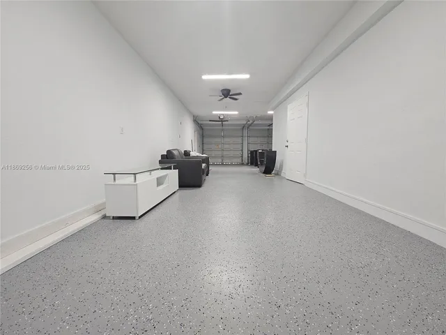 an empty room with chandelier fan and windows