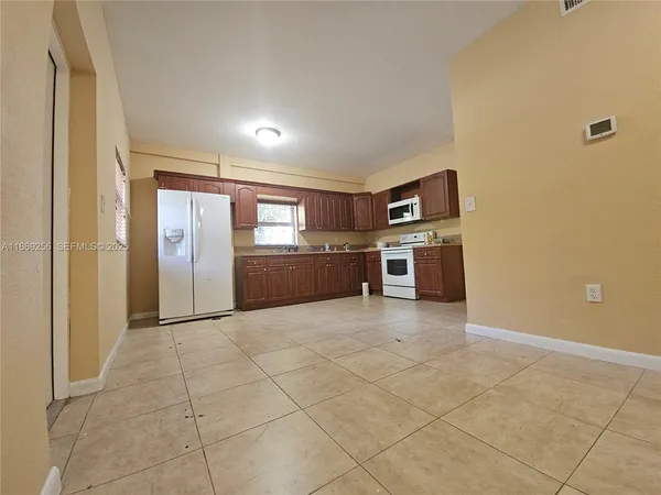 a large kitchen with stainless steel appliances granite countertop a refrigerator and a stove top oven