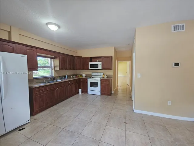 a large kitchen with stainless steel appliances granite countertop a refrigerator and a stove top oven