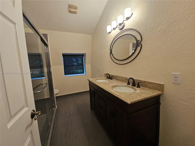 a bathroom with a granite countertop sink a mirror and a toilet