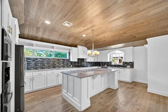 a kitchen with stainless steel appliances wooden floors and white cabinets