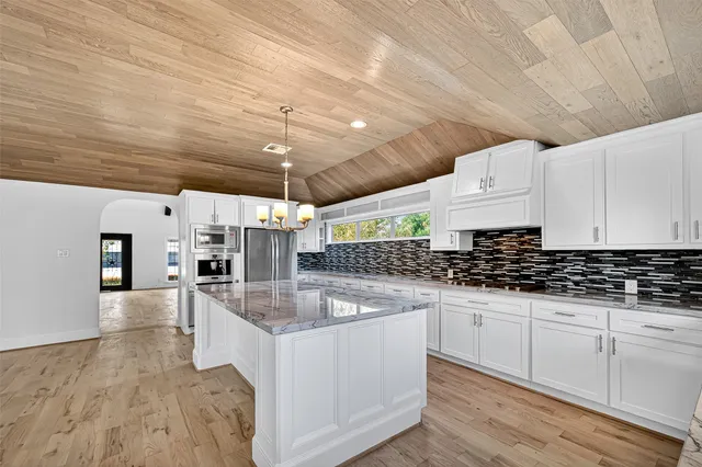 a kitchen with granite countertop a sink cabinets and wooden floor