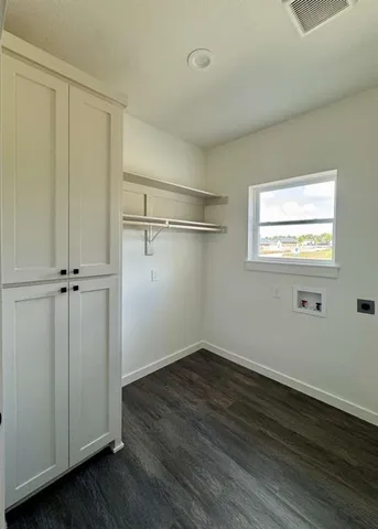 an empty room with wooden floor closet and windows