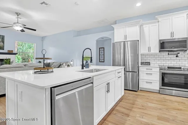 a kitchen with stainless steel appliances a sink stove refrigerator and cabinets