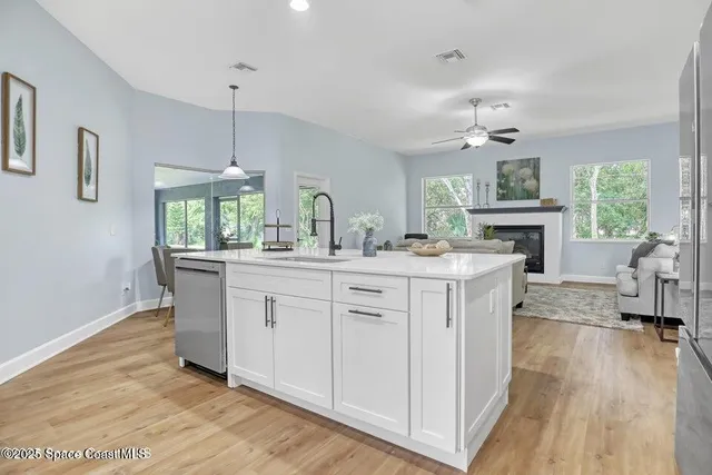a kitchen with kitchen island granite countertop a sink cabinets and wooden floor