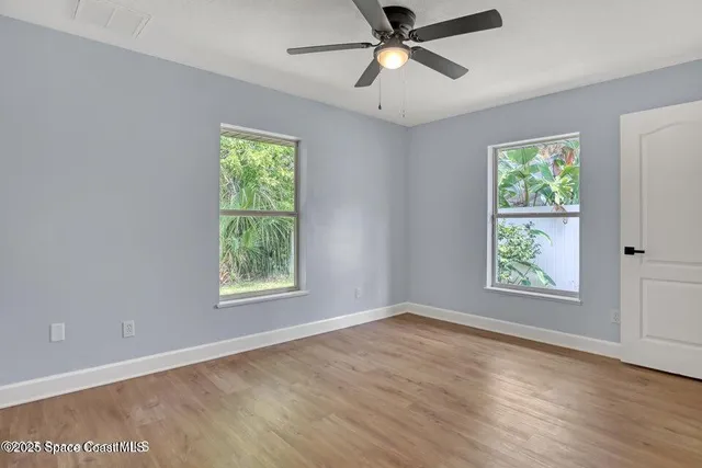 a view of an empty room with wooden floor and window