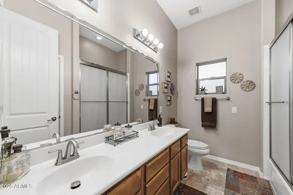 a bathroom with a sink double vanity granite and a glass door shower