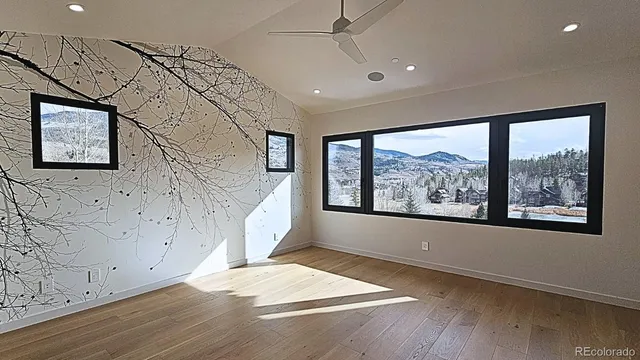 an empty room with wooden floor and windows