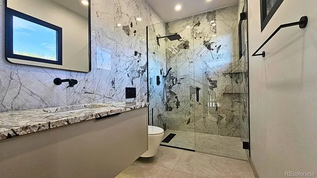 a bathroom with a granite countertop sink a toilet and shower
