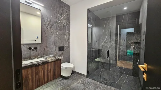 a bathroom with a granite countertop sink a toilet a mirror and shower