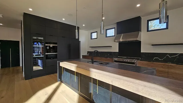 a large kitchen with stainless steel appliances a large counter top a stove and a refrigerator