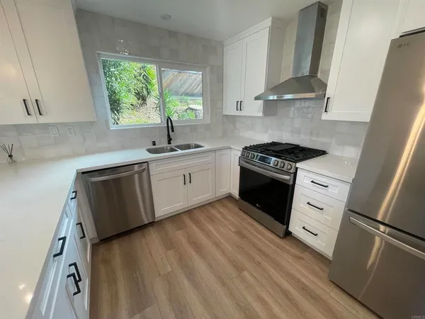 a kitchen with white cabinets appliances and a window
