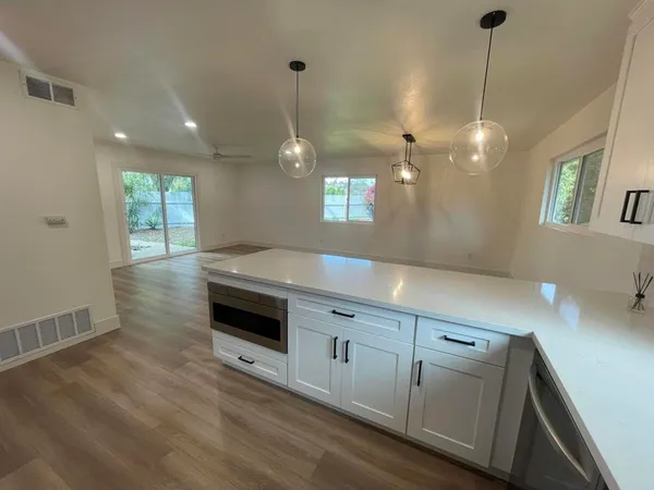 a large kitchen with granite countertop a stove and a wooden floor