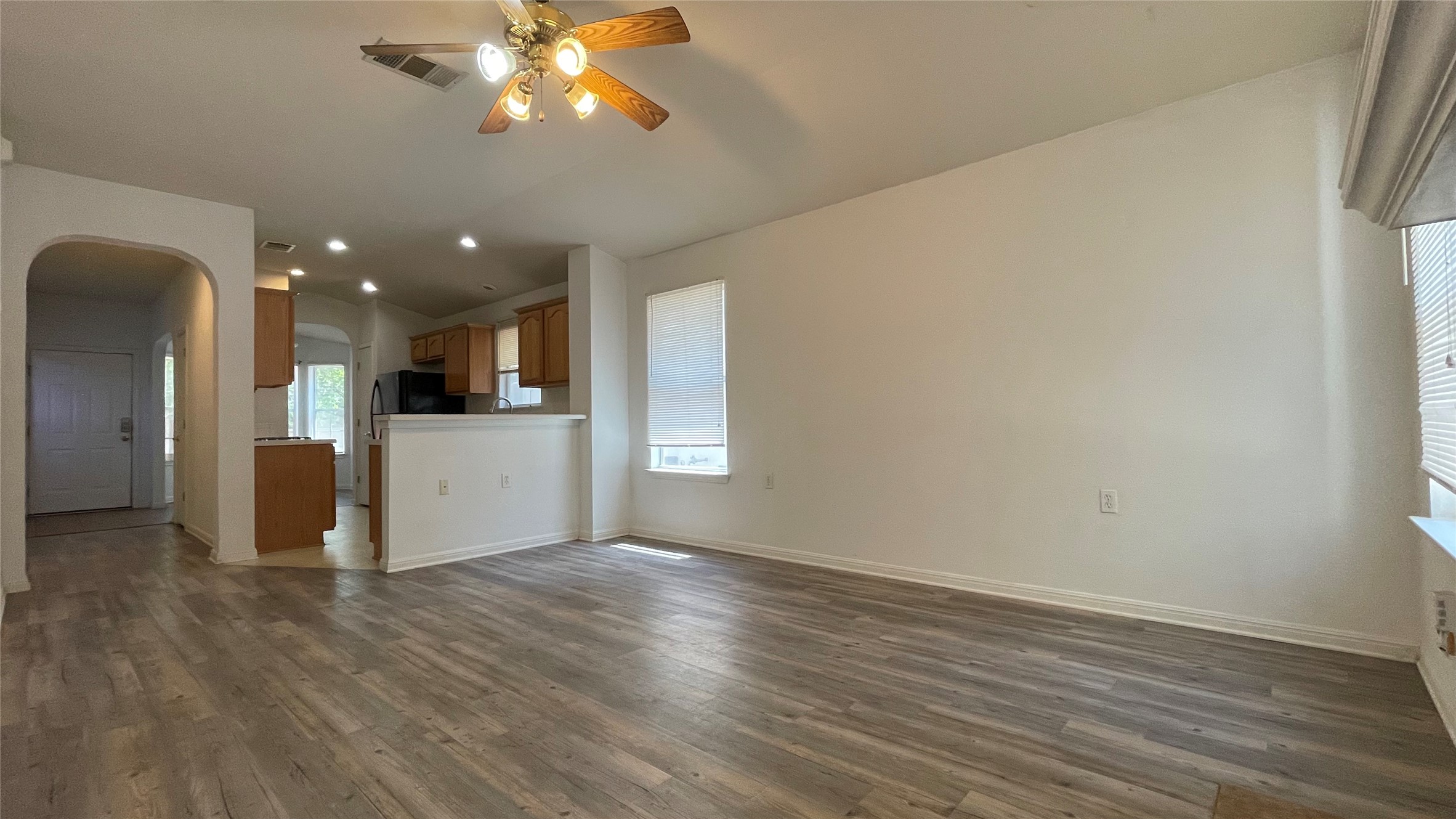5512 Steven Creek Way Austin, TX 78721 - Photo 14 of 30 Unfurnished living room with arched walkways, dark wood finished floors, a ceiling fan, lofted ceiling, and recessed lighting