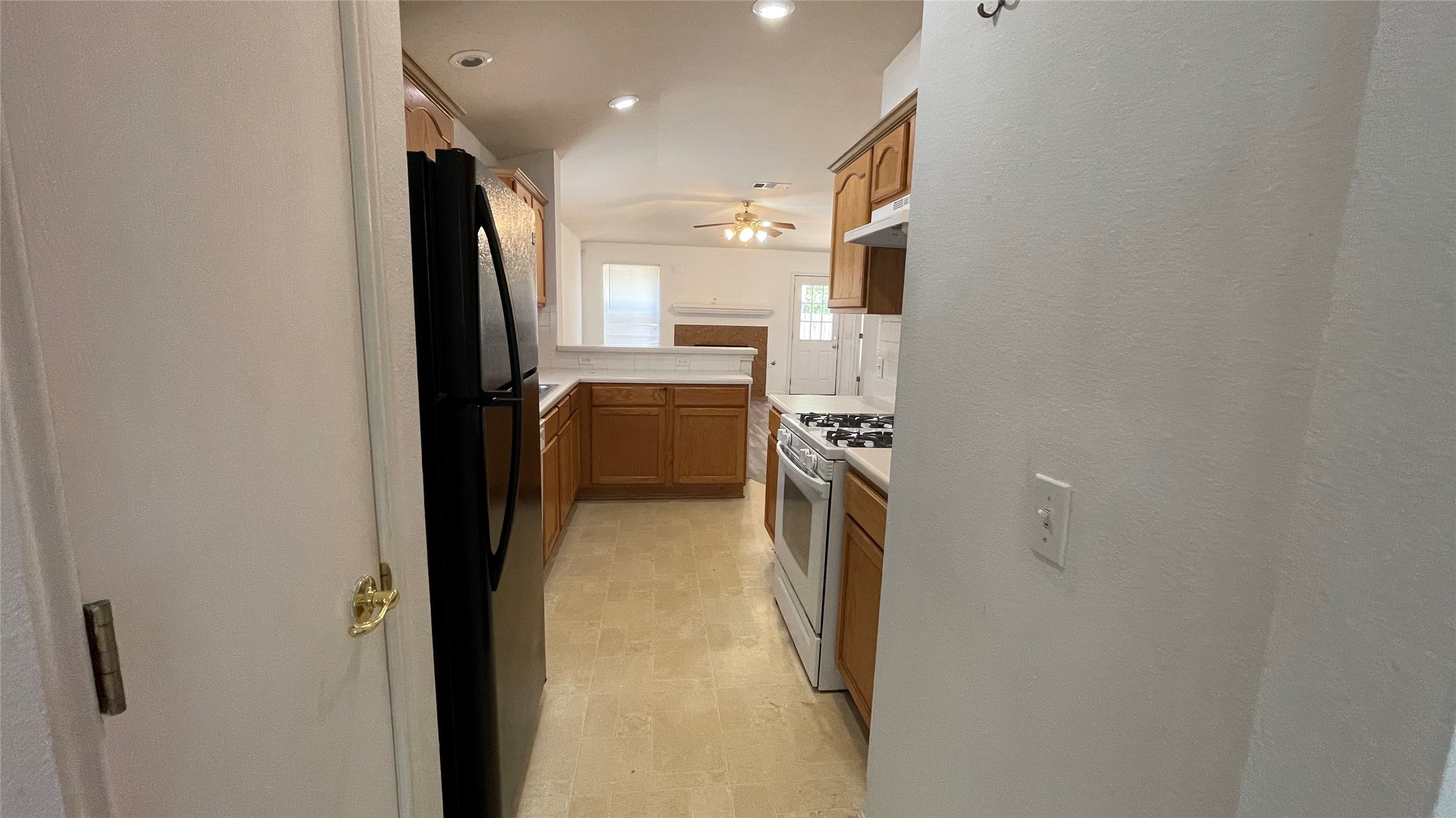 5512 Steven Creek Way Austin, TX 78721 - Photo 18 of 30 Kitchen featuring light countertops, brown cabinets, freestanding refrigerator, white gas stove, and a ceiling fan