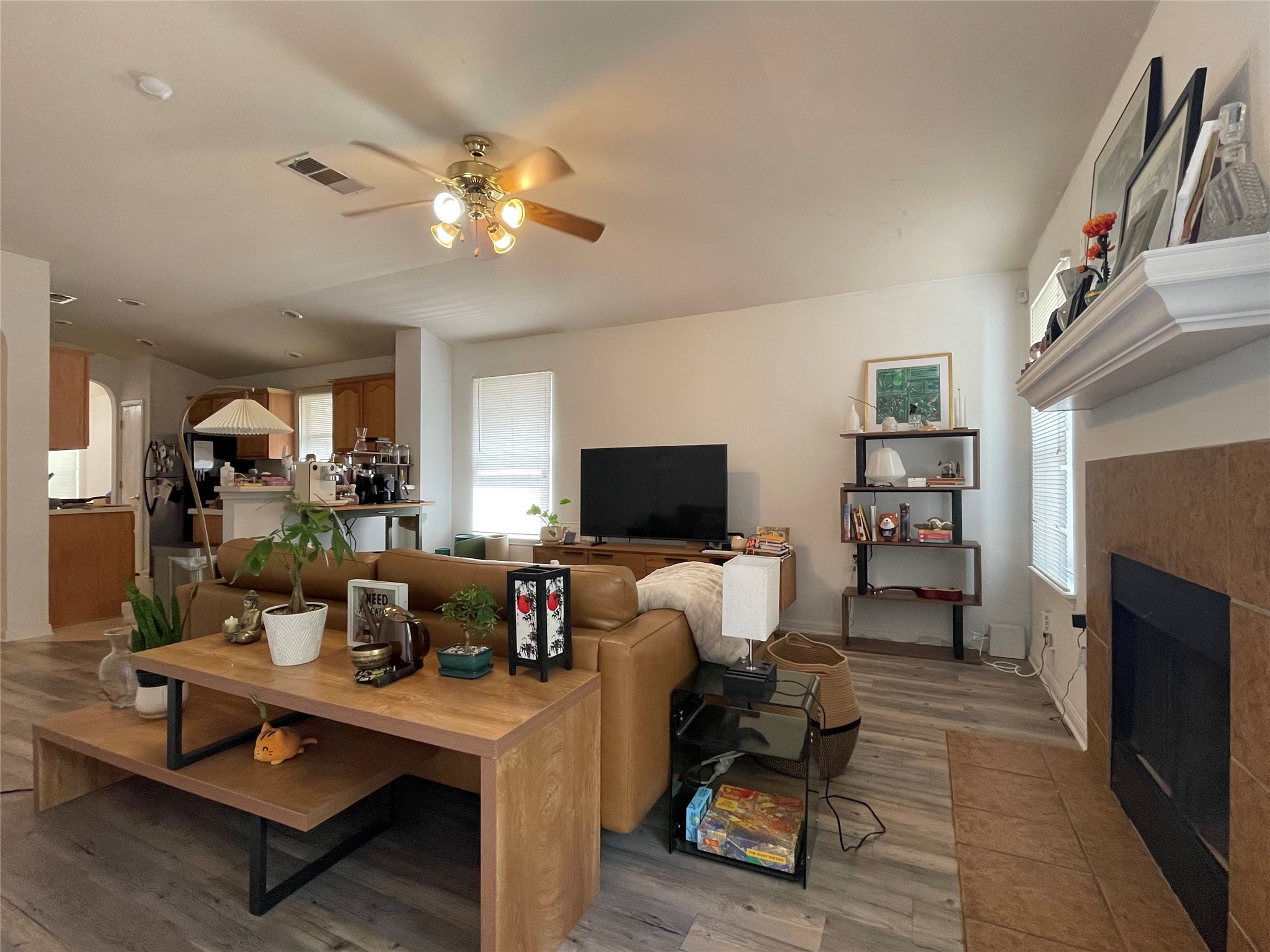 5512 Steven Creek Way Austin, TX 78721 - Photo 21 of 30 Living area with a tile fireplace, light wood finished floors, arched walkways, and a ceiling fan