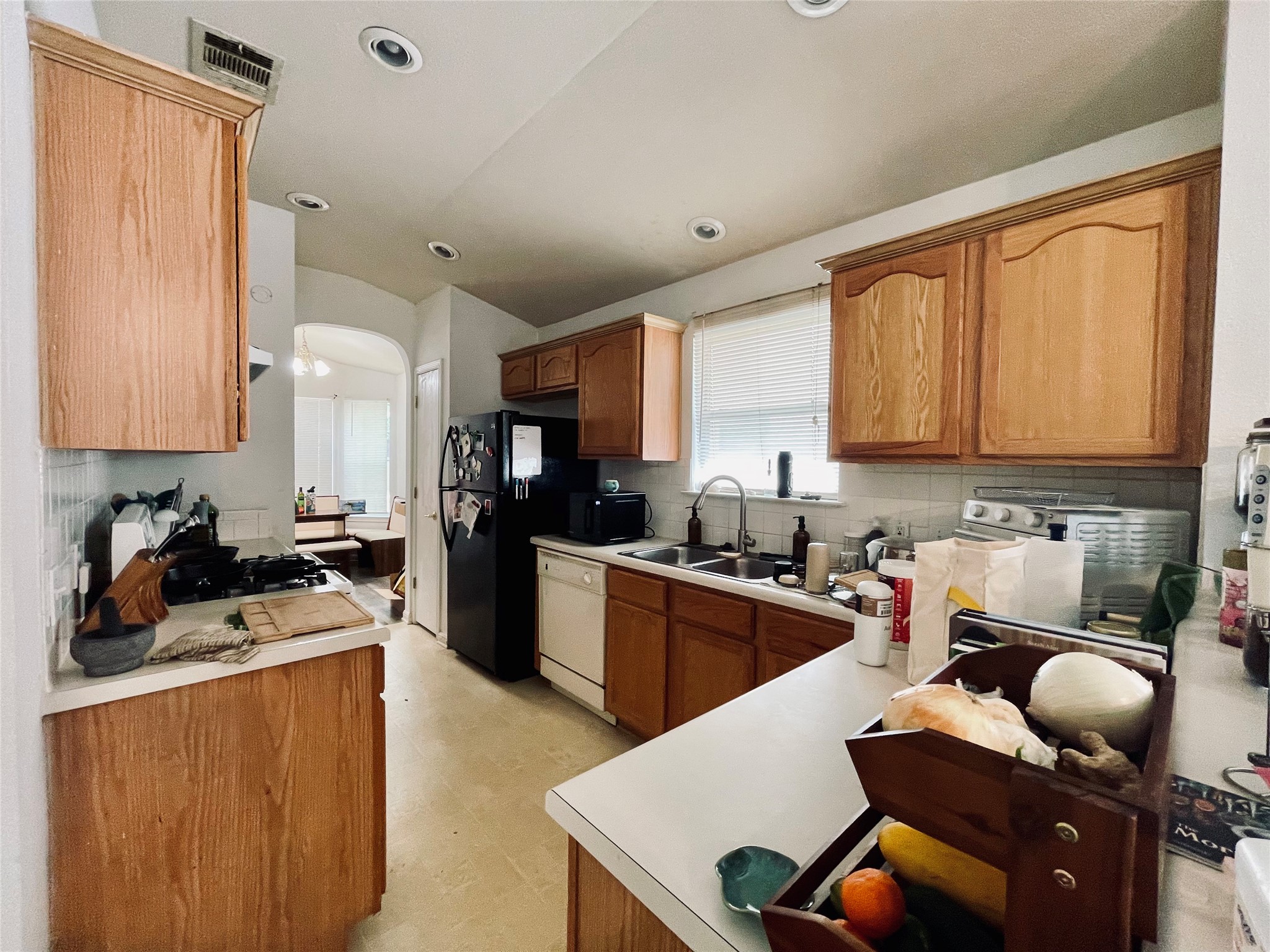 5512 Steven Creek Way Austin, TX 78721 - Photo 24 of 30 Kitchen with arched walkways, wood finish cabinetry, light countertops, decorative backsplash, and recessed lighting