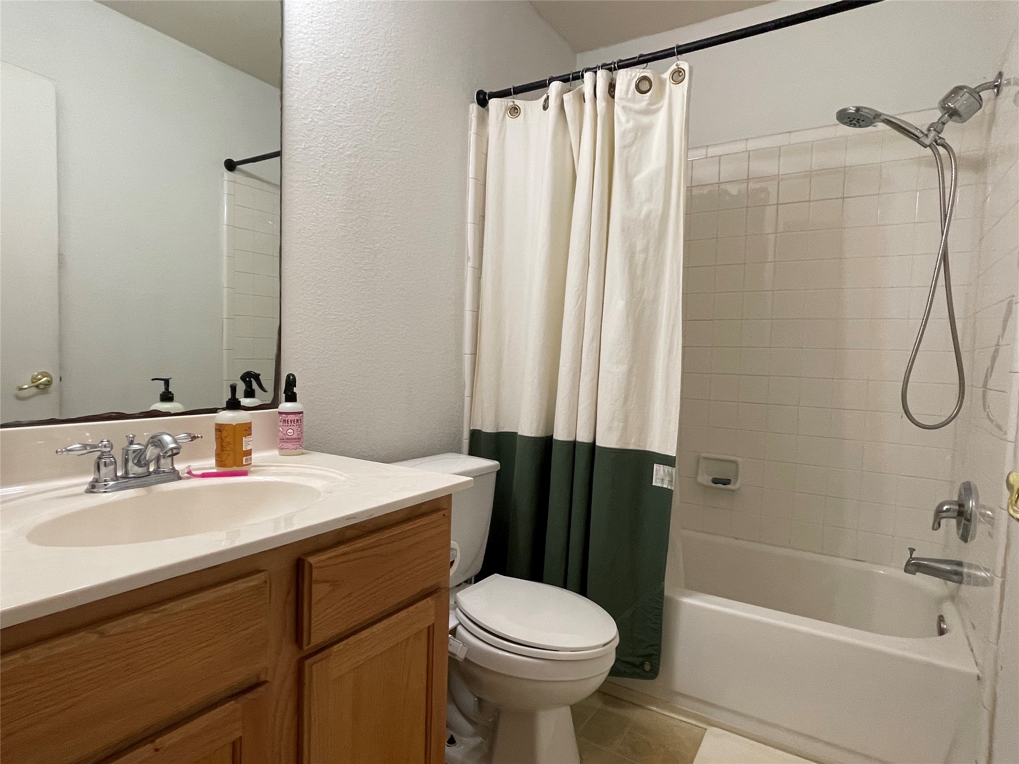 5512 Steven Creek Way Austin, TX 78721 - Photo 28 of 30 Bathroom featuring a textured wall, vanity, shower / bath combination with curtain, and light tile patterned floors