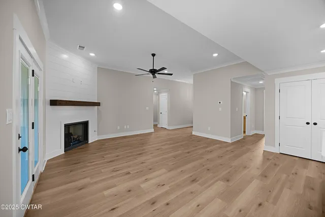 a view of a livingroom with a fireplace a ceiling fan and wooden floor