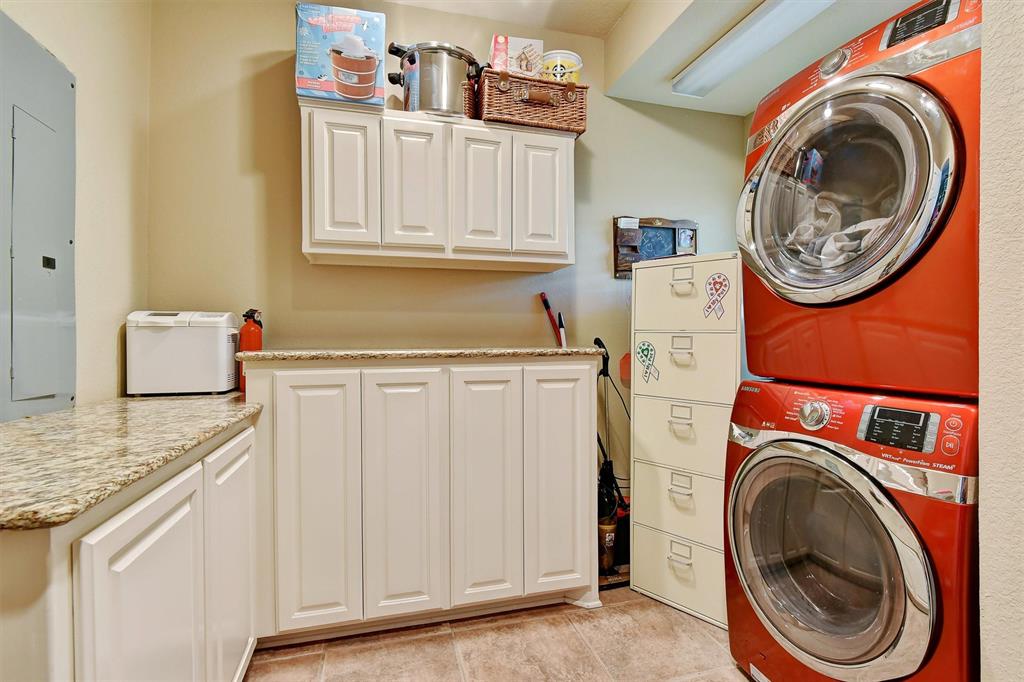 297 Cemetery Road Pottsboro, TX 75076 - Photo 16 of 40 Laundry area featuring cabinets, light tile patterned floors, electric panel, and stacked washer / drying machine
