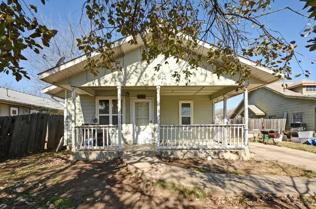 a view of a house with a large tree and wooden fence
