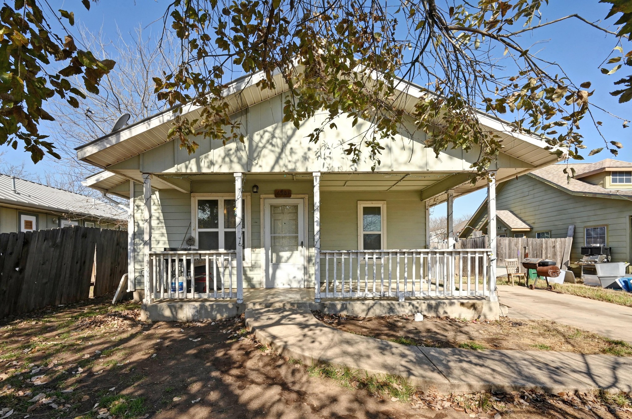 a view of a house with a large tree and wooden fence
