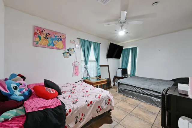 a bedroom with a bed and a flat tv screen on dresser