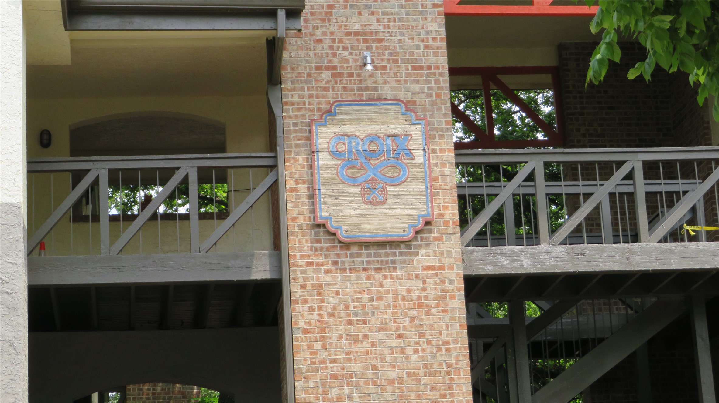806 West 24th Street, Unit 200 Austin, TX 78705 - Photo 30 of 33 A charming wooden sign, bearing the name "Croix", enhances the brick facade of this multi-level structure.