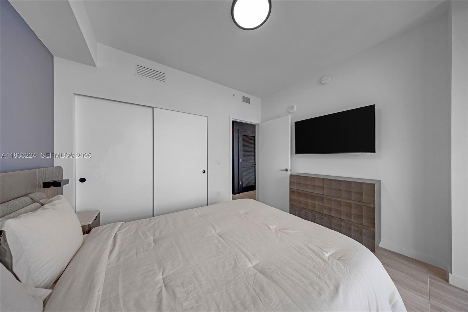580 72nd Street, Unit 910 Miami Beach, FL 33141 - Photo 50 of 60 a bedroom with a bed and a flat screen tv