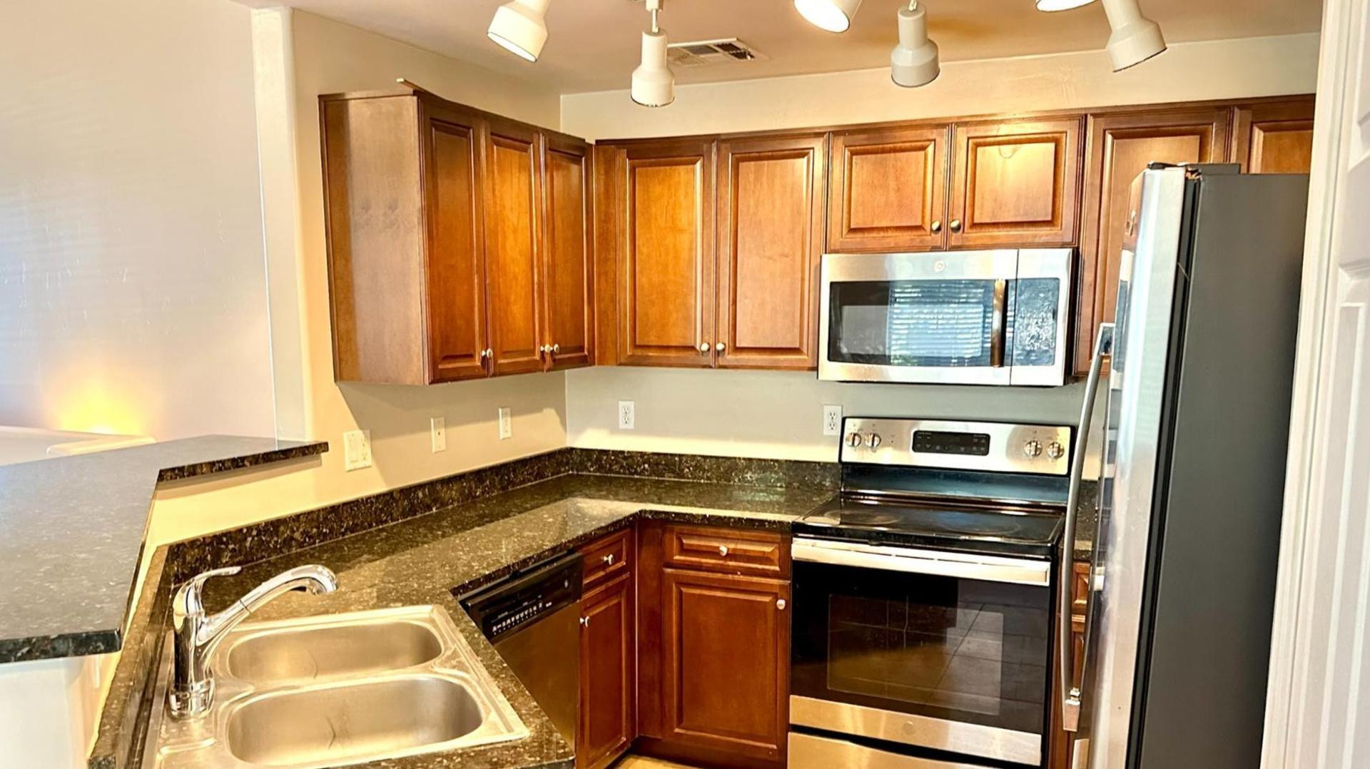 a kitchen with stainless steel appliances granite countertop a stove a sink and a microwave