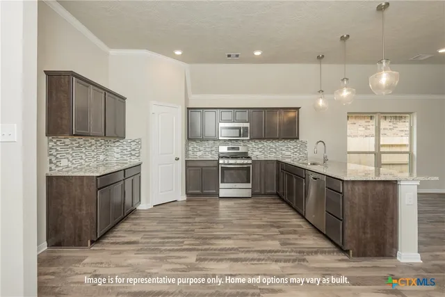a large kitchen with a large counter top a sink stainless steel appliances and cabinets