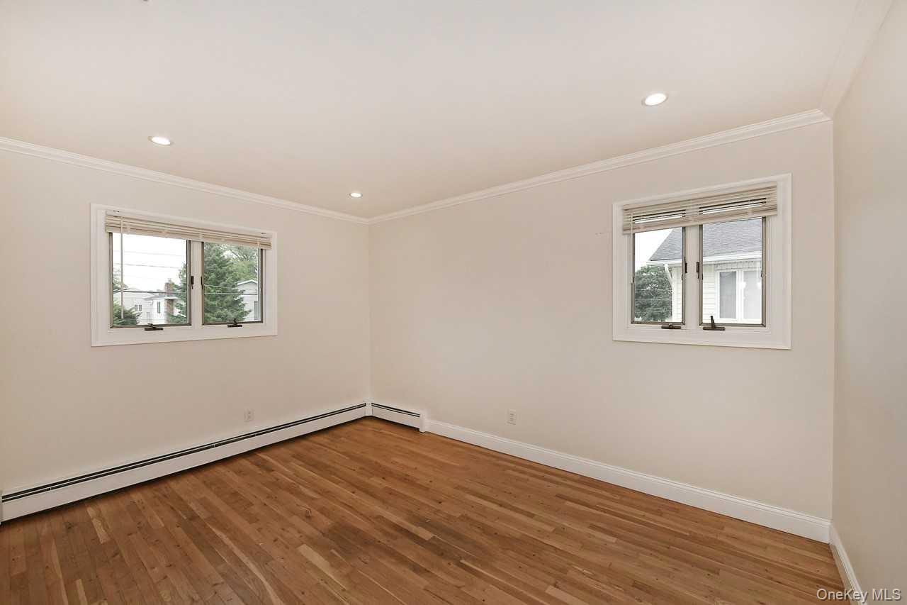 107 Beverly Road Massapequa, NY 11758 - Photo 18 of 41 a view of empty room with wooden floor and fan