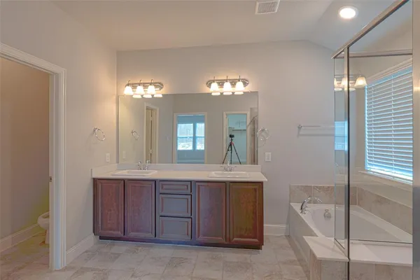 a spacious bathroom with a tub a double vanity sink and a mirror