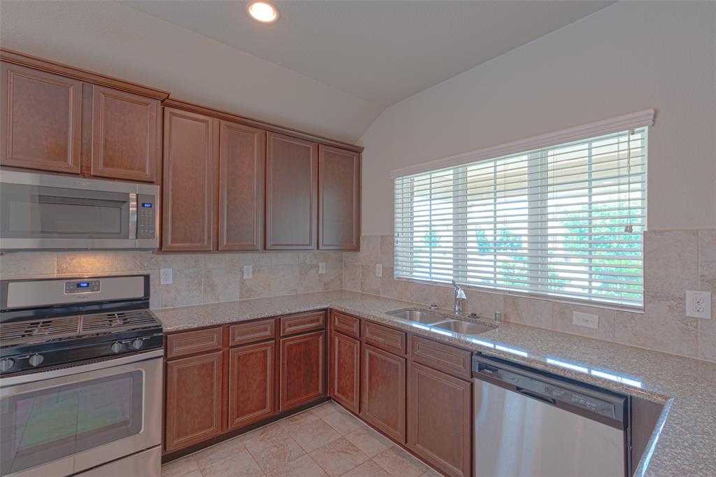616 England Street Fate, TX 75189 - Photo 5 of 40 Kitchen with stainless steel appliances, sink, light stone countertops, and light tile floors
