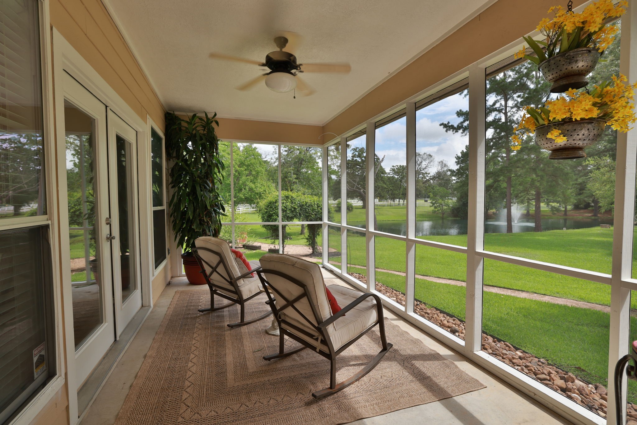 34310 High Point Drive Magnolia, TX 77355 - Photo 22 of 48 This photo showcases a serene screened-in porch room for your own cozy seating, overlooking a lush green lawn and a tranquil pond. Perfect for relaxation and enjoying nature.